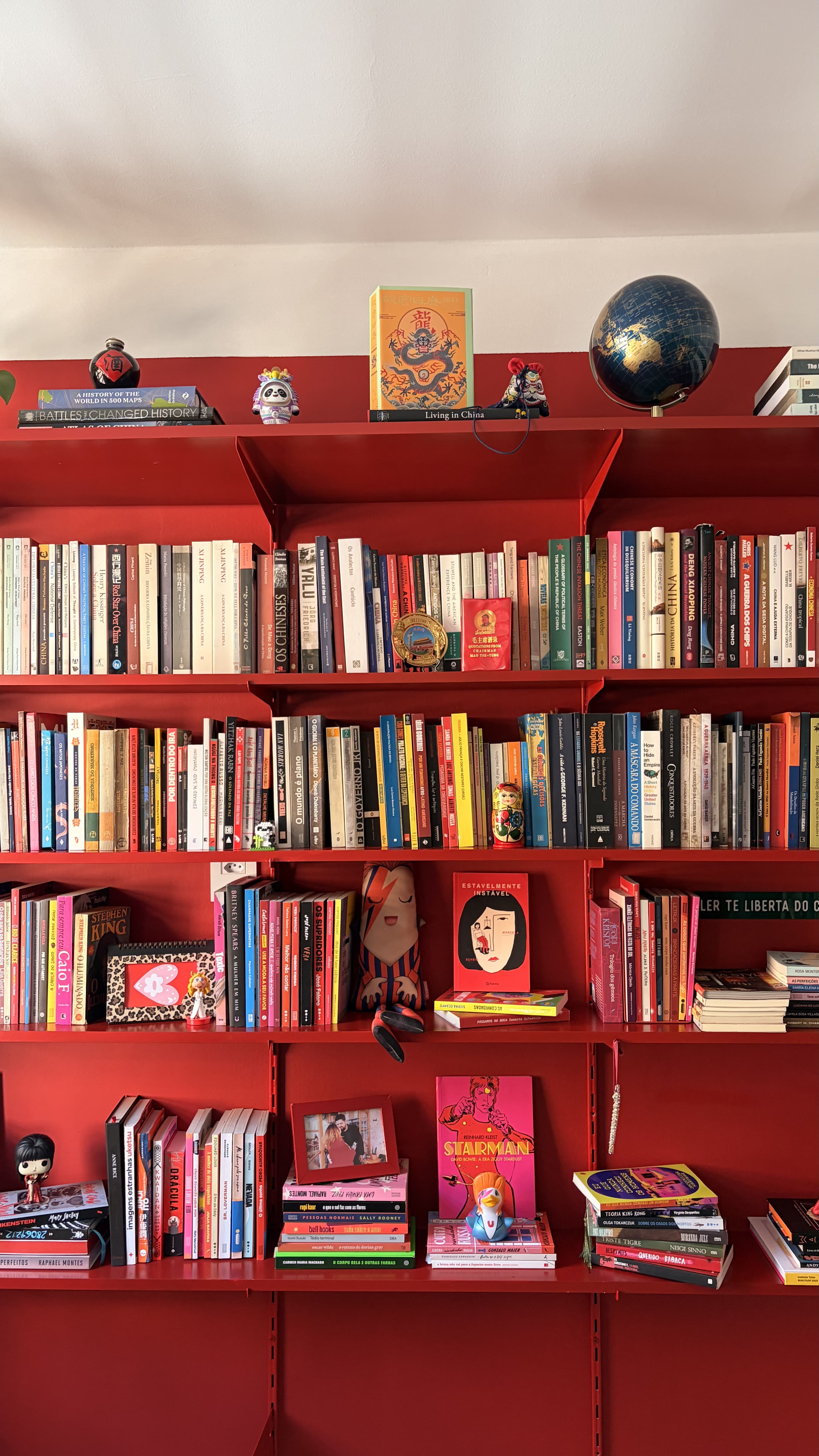 estante vermelha com livros e objetos decorativos